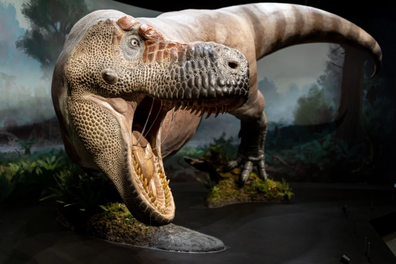 Model dinosaura v expozici muzea s realistickým prostředím.