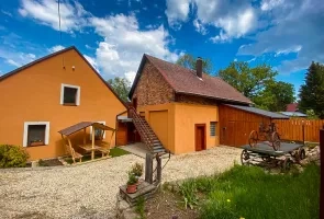 Dvě oranžové domy s dřevěným plotem na pozadí modré oblohy.
