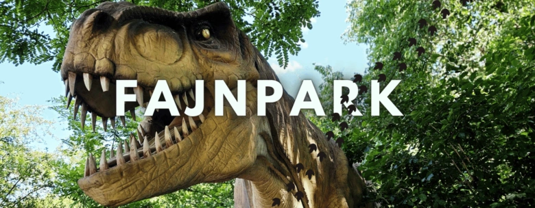 Blízký záběr hlavy tyranozaura v parku mezi stromy.