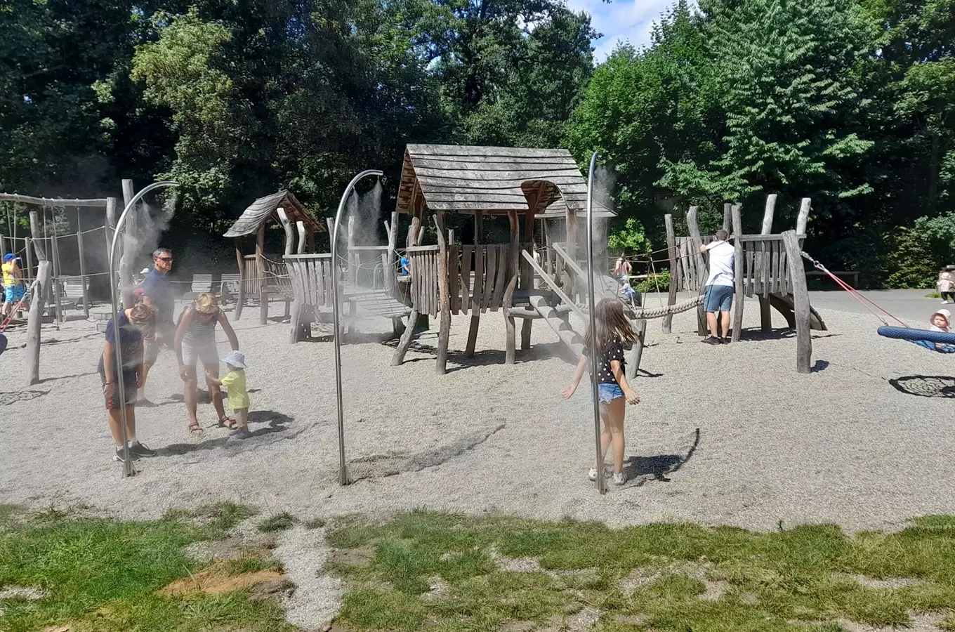Děti hrají na venkovním herním areálu s mlžícími oblouky.