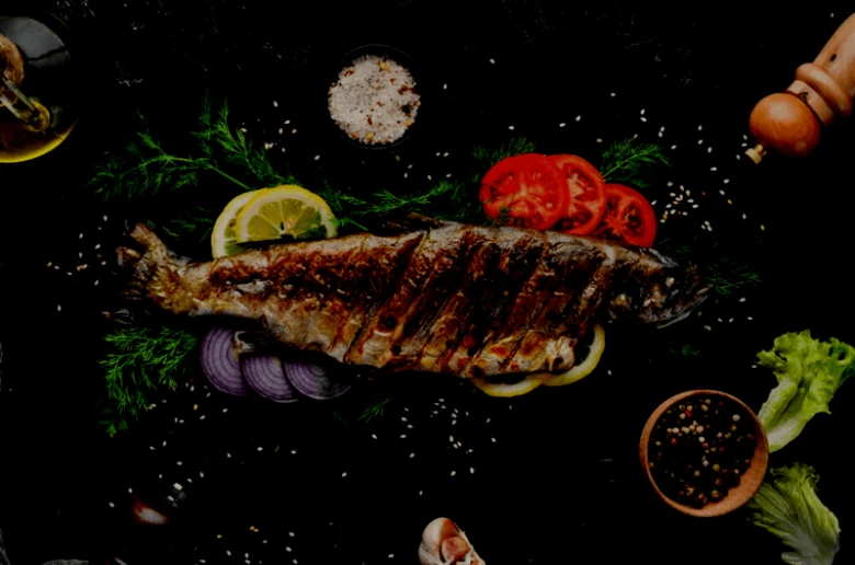 Grilovaná celá mořská ryba s citronem, rajčetou a petrželkou.